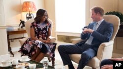 Foto resmi yang dirilis oleh Gedung Putih memperlihatkan Ibu Negara AS Michelle Obama berbincang-bincang dengan Pangeran Harry dalam upacara minum teh di Istana Kensington di tengah-tengah kunjungan Michelle Obama ke Inggris.