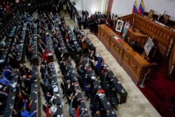 People raise their hands during the swear-in ceremony of Venezuela's National Assembly new term, in Caracas, Venezuela, Jan. 5, 2021.