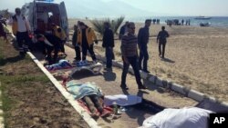 Turkish rescue workers and medics work next to the bodies of migrants laid out near an ambulance in Kusadasi, Turkey, March 24, 2017.