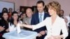 A handout picture released by the official Facebook page of Syria's First Lady Asma al-Assad shows Syrian President Bashar al-Assad (C) watching on as his wife Asma casts her vote at a polling station in Maliki.