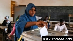 Une femme dépose son bulletin de vote dans l'urne à Niamey, le 27 décembre 2020, lors des élections présidentielles et législatives du Niger.