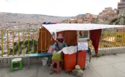 A street vendor waits for customers at her stall, where she has a sign that reads in Spanish "There is chicken and beef broth soup," for about $1, in La Paz, Bolivia, April 10, 2019.