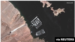 A combination of two images show aerial views of the Hemenway Harbor boat launch area on Lake Mead and Hoover Dam on the Colorado River on May 18, 2020 (top) and on July 27, 2021 (bottom).