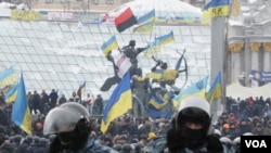 Pengunjuk rasa integrasi pro-Uni Eropa berdiri di belakang barisan polisi anti huru hara di Lapangan Kemerdekaan di Kiev, Ukraina (11/12).