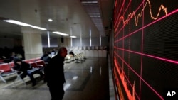 A man looks at an electronic board displaying stock prices at a brokerage house in Beijing, Jan. 26, 2016. 