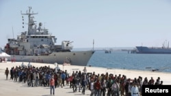 FILE - Migrants are disembarked from the Italian navy ship Vega in the Sicilian harbor of Augusta, southern Italy, May 4, 2015.