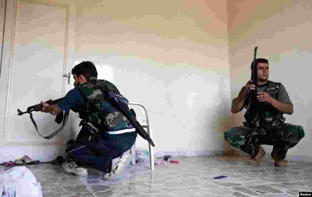 Members of the Free Syrian Army take cover inside a house during clashes with Syrian army soldiers in Aleppo's Saif al-Dawla district, August 22, 2012.