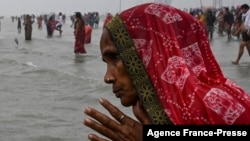A Hindu pilgrim in India prays as she takes a holy dip at the confluence of Ganges and the Bay of Bengal during the Gangasagar Mela on the occasion of Makar Sankranti, Jan. 14, 2022. 