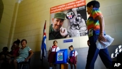 Dengan latar poster mendiang Fidel Castro, seorang perempuan tiba di tempat pemungutan suara untuk memberikan suara pada pemilihan kepala daerah di Havana, Kuba, 26 November 2017.