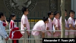 FILE - Chinese students wait outside the U.S. Embassy for their visa application interviews in Beijing, China.