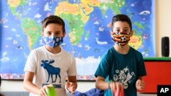 Nine years old boys Tom, left, and Patrizio wear face masks to protect against the coronavirus as they show a musical contribution, without singing, at the Lenneberg Primary and Secondary School in Mainz, Germany, Monday, Aug. 17, 2020. German…