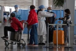 Health workers screen people entering the Capital International Airport terminal 3 in Beijing, March 12, 2020.