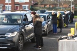 FILE - Staff members deliver injections of the first dose of the Pfizer-BioNTech COVID-19 vaccine to patients in their cars at a drive-in vaccination center in Hyde, Greater Manchester, northwest England, Dec. 17, 2020.