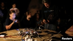 FILE - People use a generator in a municipal truck to charge cellphones during a blackout in Caracas, Venezuela, July 22, 2019.