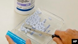 FILE- A pharmacy tech poses for a picture with pills of the generic version of Vicodin, in Edmond, Okla. The U.S. Centers for Disease Control and Prevention says not only do pain medications run a high risk of addicting the user, but they can actually make patients' chronic pain worse. 