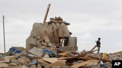 Shi'ite fighters known as Houthis stand on the rubble of a house destroyed by a Saudi airstrike in Sana'a, Yemen, Wednesday, Aug. 26, 2015.