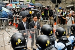 FILE - Lawmakers Jeremy Tam and Alvin Yeung of the Hong Kong Civic Party speak in front of a row of riot police officers during a demonstration against a proposed extradition bill in Hong Kong, China, June 12, 2019.