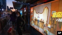 Residents stand near an ad promoting the Nov. 11 Sales Day in Beijing when Chinese consumers are expected to spend tens of billions on everything from fresh food to luxury goods , as the country recovers from the coronavirus pandemic.