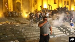Opposition demonstrators run away as police fired a volley of tear gas against them at Georgian Parliament during a protest in Tbilisi, Georgia, June 21, 2019. 
