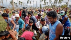 Survivors of typhoon Haiyan rush to grab fresh water delivered by a U.S. military helicopter to their isolated village north of Tacloban, Nov. 17, 2013. 