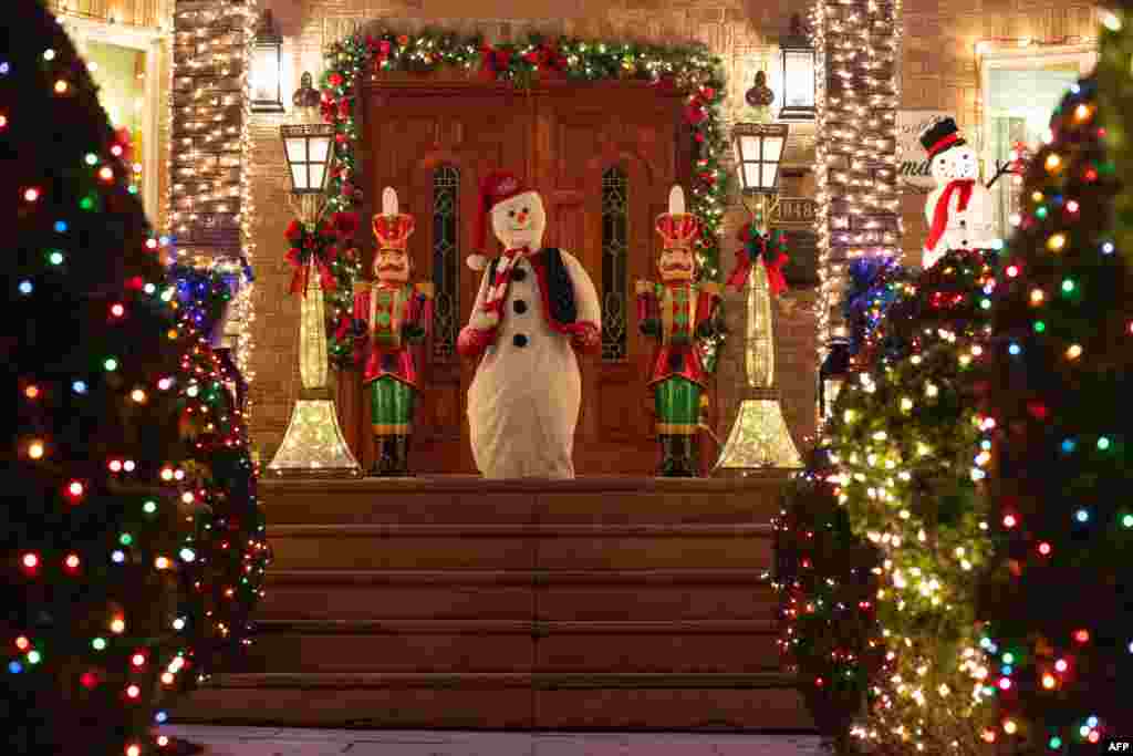 Un hombre de nieve junto a unos cascanueces custodian para Navidad un hogar en el barrio de Dyker Heights de Brooklyn el 15 de diciembre de 2020. [AFP]