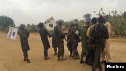FILE - Boko Haram militants (in camouflage) embrace and shake hands with Boko Haram prisoners, released in exchange for a group of 82 Chibok girls, who were held captive for three years by Islamist militants, near Kumshe, Nigeria, May 6, 2017.