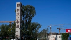 A woman walks by an Evergrande new housing development in Beijing on Sept. 22, 2021. 