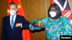 Chinese Foreign Minister Wang Yi and his Kenyan counterpart, Raychelle Omamo, bump elbows during a news conference in Mombasa, Kenya, Jan. 6, 2022. 