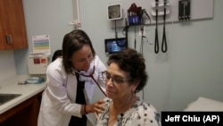 In this April 9, 2019 photo, Dr. Megan Mahoney, left, examines patient Consuelo Castaneda at the Stanford Family Medicine office in Stanford, California. (AP Photo/Jeff Chiu)