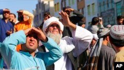 Ljudi gledaju u tela ubijenih koje su talibani obesili o kran na glavnom trgu u gradu Heratu, u zapadnom Avganistanu, 25. septembra 2021.