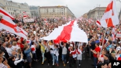 Demonstrators carry a huge historical flag of Belarus as thousands gather for a protest at the Independence square in Minsk, Belarus, Aug. 23, 2020.