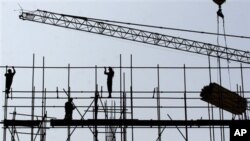 FILE - Chinese construction workers labor at a highrise building under construction in Beijing.