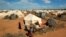 Refugees stand outside their tent at the Ifo Extension refugee camp in Dadaab, near the Kenya-Somalia border in Garissa County, Kenya on Oct. 19, 2011. 