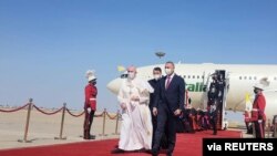 Iraqi Prime Minister Mustafa Al-Kadhimi walks with Pope Francis upon his arrival at Baghdad International Airport, in Baghdad, Iraq, March 5, 2021. 