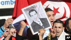 A woman holds a picture of Tunisia's deposed leader Zine El Abidine Ben Ali, reading 'Wanted', during a demonstration showing solidarity with Tunisians, in Marseilles, France , Jan. 15, 2011