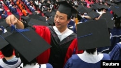A man adjusts a student's mortar board during the graduation ceremony at Fudan University in Shanghai June 28, 2006. (File)