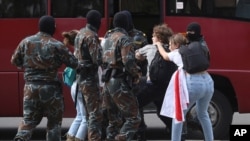 FILE - Masked men detain students during a protest against official presidential election results, in Minsk, Belarus, Sept. 1, 2020. 