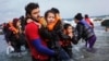 FILE - A volunteer life-guard helps a young girl out of the sea after the boat she used along with her family and other Afghan refugees to cross part of the Aegean from the coast of Turkey to Lesbos crashed on a rock off the island's coast.
