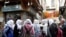 FILE - A group of school girls stand outside shops in the old city of Damascus, Syria, March 12, 2020.