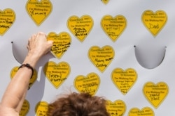 COVID-19 survivors gather at City Hall Park and place stickers representing lost relatives on a wall Aug. 7, 2021, in New York, as part of the largest nationwide day of awareness and action for COVID-19 survivors.