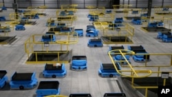 In this Dec. 17, 2019, photo dozens of Amazon robots transport packages from workers to chutes that are organized by zip code, at an Amazon warehouse facility in Goodyear, Ariz. (AP Photo/Ross D. Franklin)