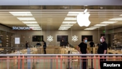 Des employés se tiennent devant l'Apple Store au centre commercial Destiny USA, à Syracuse, New York, États-Unis, le 10 juillet 2020. REUTERS / Maranie Staab