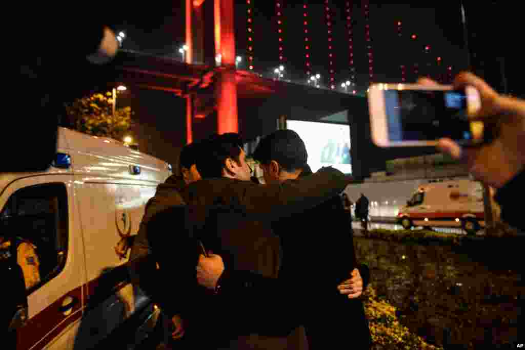 Youths embrace near the scene of an attack in Istanbul, early Jan. 1, 2017. An assailant believed to have been dressed in a Santa Claus costume and armed with a long-barreled weapon, opened fire at a nightclub in Istanbul's Ortakoy district.