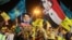 Hezbollah supporters wave Hezbollah and Syrian flags with a picture of Syrian President Bashar al-Assad, right, and Hezbollah leader Sheik Hassan Nasrallah, left, during a rally marking the sixth anniversary of the 2006 Israel-Hezbollah war, in Beirut, Le