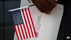 ARCHIVO - Maweya Babekir, de Iowa City, Iowa, sostiene una bandera antes de prestar juramento de lealtad durante una ceremonia de naturalización en Principal Park, el viernes 26 de junio de 2020, en Des Moines, Iowa.