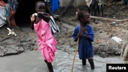 Children walk through mud in an internally displaced persons camp inside the United Nations base in Malakal, South Sudan, July 23, 2014.