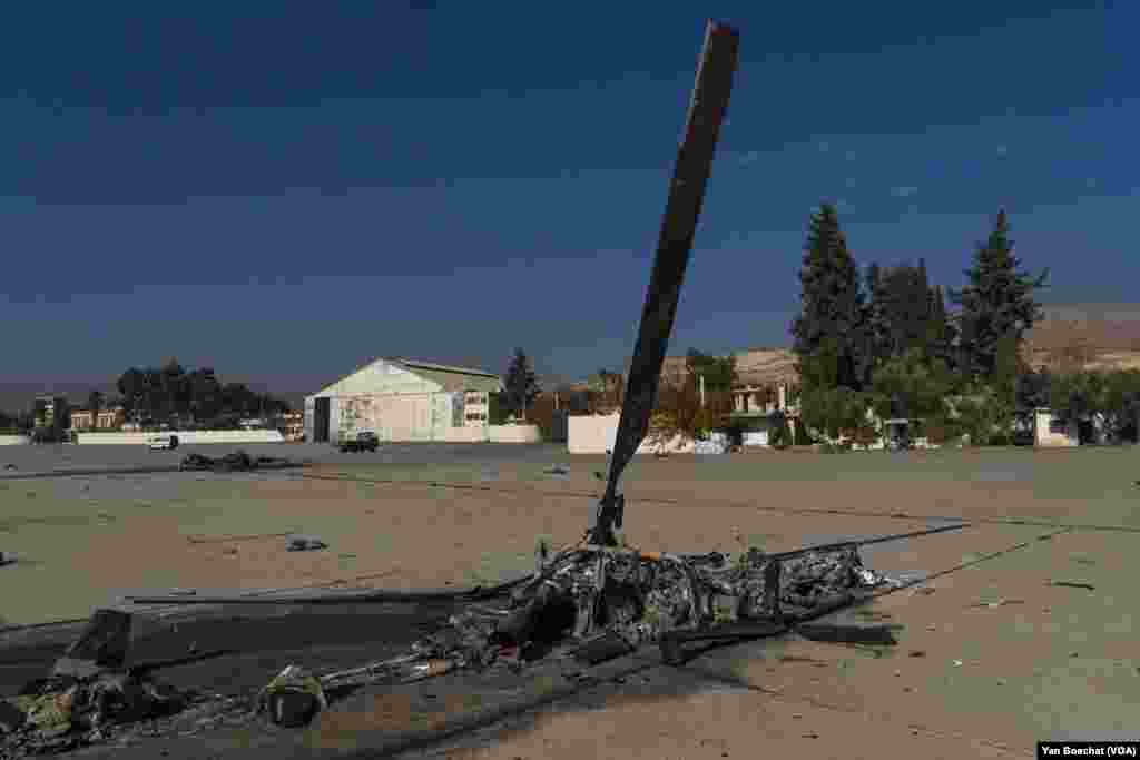 The remains of a helicopter destroyed by an Israeli air strike is still visible near the hangars of the Mazzeh air base, in Damascus, Syria, on Dec. 19, 2024. (Yan Boechat/VOA)