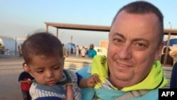 FILE - British aid worker Alan Henning holding a child in a refugee camp on the Turkish-Syrian border.