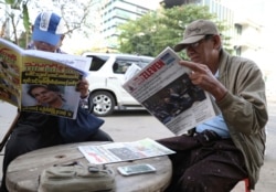 Locals read through newspapers leading with Myanmar leader Aung San Suu Kyi at the International Court of Justice hearing outside a roadside shop in Yangon, Myanmar, Dec. 12, 2019.