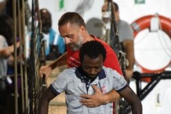 A migrant is helped off the Spanish rescue ship Open Arms NGO, as it arrives in Lampedusa, Italy, Aug. 20, 2019.